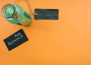 drink-bottle-with-label-inscription-with-alloween-congratulation-orange-background_23-2147895087