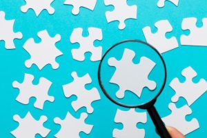 white-jigsaw-piece-seen-through-magnifying-glass-blue-white-background_23-2148207369