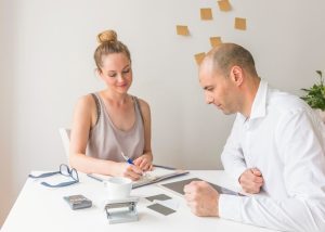 businessman-looking-businesswoman-writing-diary-workplace_23-2147880556