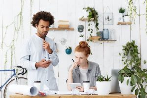 concentrated-serious-male-engineer-messaging-ceo-using-mobile-phone-standing-office_273609-14121