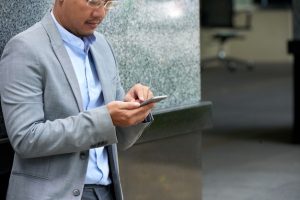 cropped-man-reading-text-message-his-smartphone-standing-office-building_1098-19118