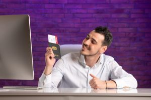 front-view-office-worker-sitting-his-working-place-holding-tickets-passport_179666-25579