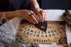 hands-using-old-wooden-ouija-board-high-angle_23-2149409484