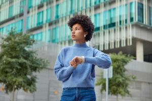 outdoor-shot-thoughtful-young-woman-with-curly-hair-checks-time-wristwatch-waits-someone-street-concentrated-into-distance-wears-casual-jumper-jeans-stands-urban-setting_273609-56603