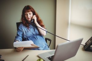 pregnant-businesswoman-talking-telephone-while-working_107420-95757