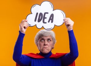 senior-woman-superhero-wearing-red-cape-holding-speech-bubble-sign-with-word-idea-her-head-making-wry-mouth-with-disappointed-expression_141793-108974