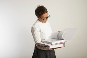 serious-unhappy-looking-young-female-teacher-blouse-skirt-is-reading-pages-from-thick-binder-isolated-white_346278-1148