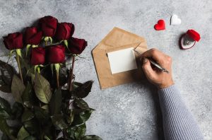 valentines-day-man-hand-holding-pen-writing-love-letter-with-greeting-card_114579-433