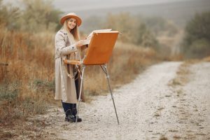 woman-brown-coat-painting-field_1157-35001