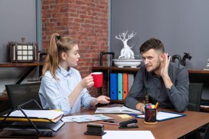 young-harworking-female-worker-her-male-co-worker-sitting-table-discussing-one-important-issue-office_140725-106332