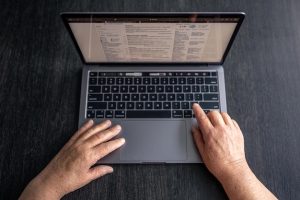 aged-woman-uses-laptop-top-view-hands-close-up_169016-27693