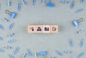 business-office-concept-with-wooden-blocks-with-icons-paperclips-binder-clips-top-view_176474-10394