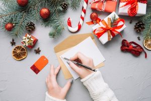 christmas-composition-with-hands-writing-letter_23-2147722774