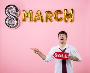 front-view-young-male-holding-red-sale-nameplate-with-march-decoration-pink-background-man-feminine-color-party-shopping-money-present-equality-holidays_140725-157356
