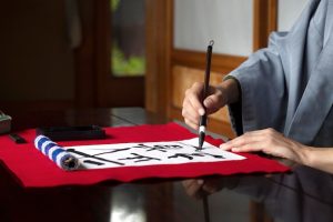 man-practicing-japanese-handwriting-with-brush_23-2149124211