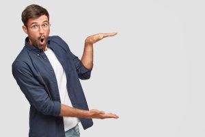stunned-unshaven-male-with-shocked-facial-expression-gestures-with-hands-shows-size-height-something-dressed-fashionable-shirt-isolated-white-wall-copyspace_273609-16324-1