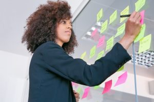 successful-pretty-businesswoman-writing-sticker-with-marker-thoughtful-confident-curly-female-manager-sharing-idea-project-making-note-brainstorming-business-training-concept_74855-7829