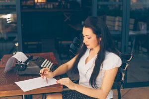 woman-sitting-writing-paper-cafe-terrace-white-shirt-daytime_176474-4905
