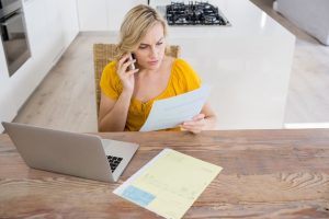 woman-talking-mobile-phone-while-looking-bill-kitchen_1170-439-1