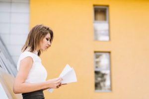 young-businesswoman-standing-outside-office-reading-documents_23-2147941481-1