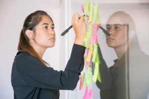 young-latin-businesswoman-writing-sticker-with-marker-focused-confident-beautiful-brunette-female-manager-sharing-idea-project-making-note-brainstorming-business-training-concept_74855-7866